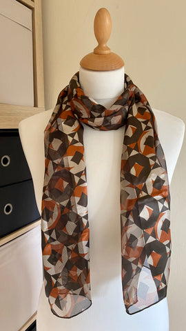 This abstract design scarf is made with 100% polyester, providing a silky smooth feel against the skin. The shades of brown add a touch of sophistication, making it a stylish and versatile addition to any wardrobe. Measuring 150cm x 35cm, it offers both fashion and functionality.