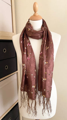 Experience the elegance of this chestnut brown scarf, made with a soft silky feel that drapes beautifully and has a light-catching sheen. It's delicately embroidered with tiny flowers and made of 100% polyester. Measuring 63cm x 160cm excluding the fringe, it's perfect for any occasion.