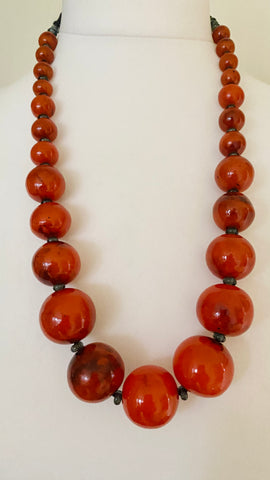 Elevate your look with this statement necklace, it features a beautiful burnished orange colour that adds a pop of warmth to any outfit. The hoop and button fitting allows for easy and secure wear making it a practical and stylish addition to your jewellery collection. 