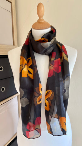 This vibrant scarf is crafted from 100% Polyester, offering a luxurious, silky feel, in shades of red black and gold, it measures 150cm x 35cm.