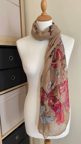 This stylish butterfly scarf in taupe is perfect for brightening up your outfit. Made from 100% polyester, it's soft, lightweight, and measures 180cm x 80cm - allowing for multiple styling options. Create a unique look with the eye-catching, random butterfly design.