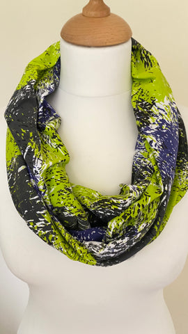 abstract design infinity scarf. The vibrant colours of lime green, lilac, black, and white combine to create a stunning pattern, while the soft and crease resistant fabric makes for a hassle free wearing experience